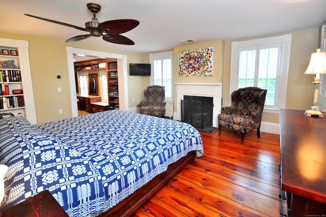 794 Main St, Somers, CT 06071 - bedroom featuring hardwood / wood-style flooring, multiple windows, radiator heating unit, and a fireplace with flush hearth