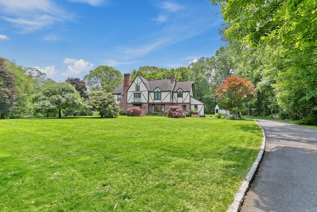 5 Tall Oaks Rd, Wilton, CT 06897 - tudor house featuring a front yard, a chimney, and view of scattered trees