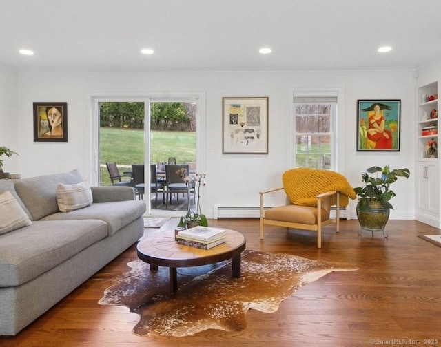 living room with healthy amount of natural light, wood finished floors, crown molding, a baseboard heating unit, and recessed lighting