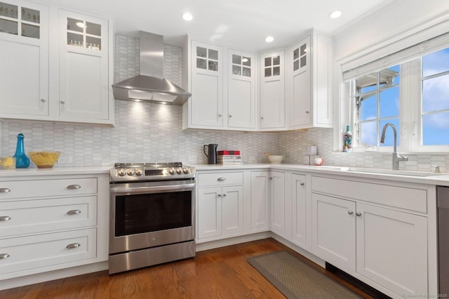 kitchen featuring electric stove, wall chimney exhaust hood, a sink, light countertops, and dark wood-style floors