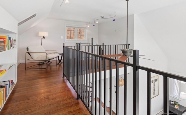 hall with an upstairs landing, wood finished floors, and vaulted ceiling