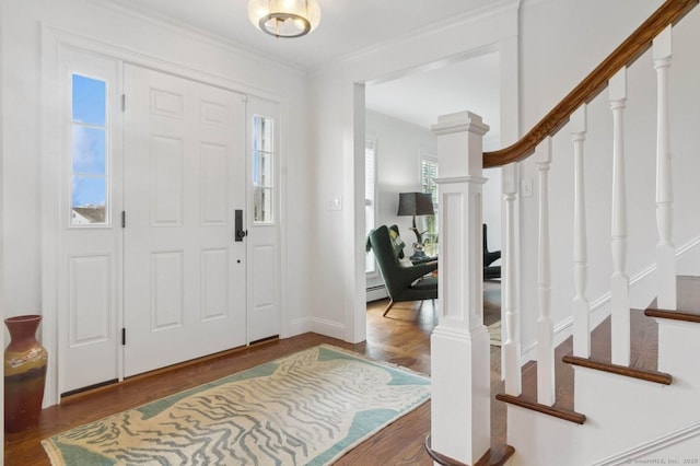 foyer entrance featuring stairs, wood finished floors, baseboard heating, crown molding, and baseboards
