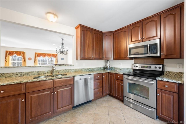kitchen with light stone counters, a sink, a chandelier, and appliances with stainless steel finishes