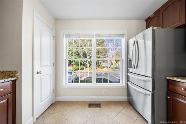 kitchen featuring light stone counters, light tile patterned floors, baseboards, stainless steel refrigerator with ice dispenser, and visible vents