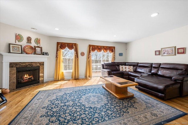 living area with recessed lighting, a premium fireplace, wood finished floors, and baseboards