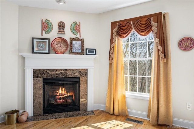 details featuring a premium fireplace, wood finished floors, visible vents, and baseboards
