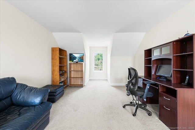 office area featuring lofted ceiling, baseboards, and light colored carpet
