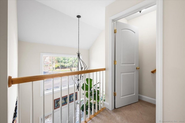 hallway with vaulted ceiling, baseboards, and carpet floors
