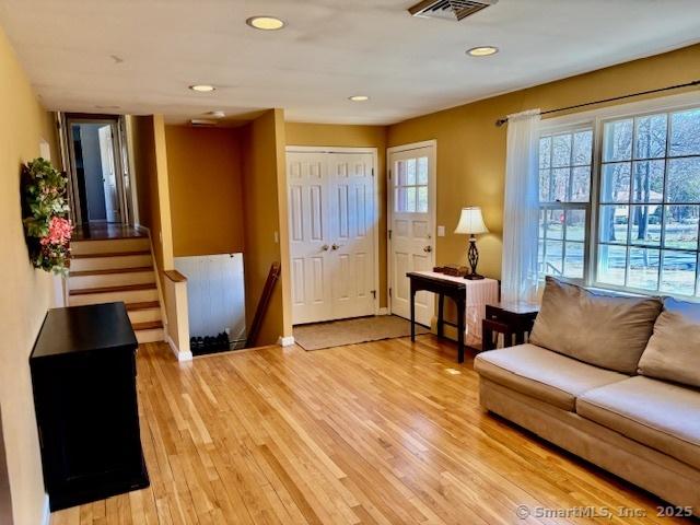 living area with stairway, light wood finished floors, visible vents, and recessed lighting