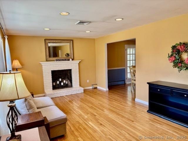 living room featuring visible vents, baseboards, light wood finished floors, and baseboard heating