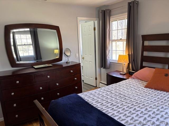 bedroom with a baseboard radiator and wood finished floors
