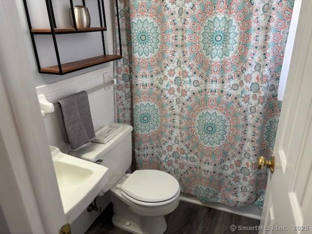 full bath with tile walls, toilet, a shower with curtain, and wood finished floors
