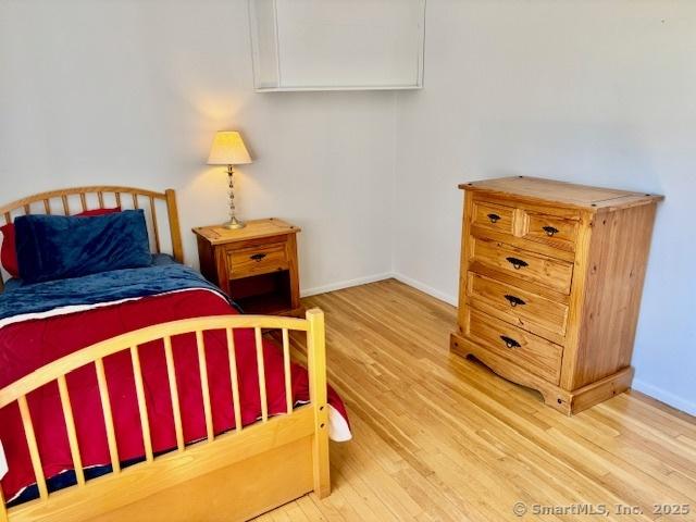 bedroom with baseboards, attic access, and wood finished floors