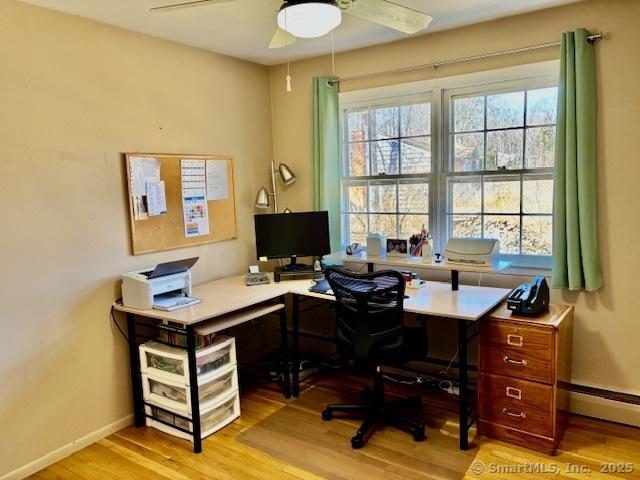 home office featuring baseboard heating, wood finished floors, ceiling fan, and baseboards