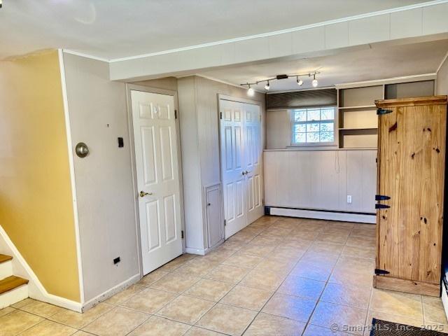 spare room featuring stairway, light tile patterned floors, a baseboard radiator, and baseboards