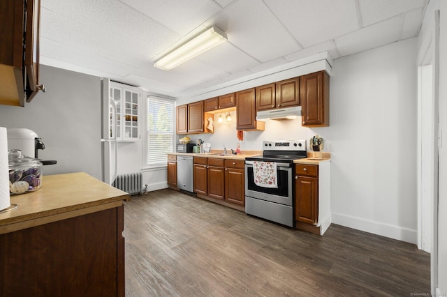 56-58 E Main St, Stonington, CT 06355 - kitchen featuring radiator heating unit, under cabinet range hood, dark wood finished floors, and appliances with stainless steel finishes