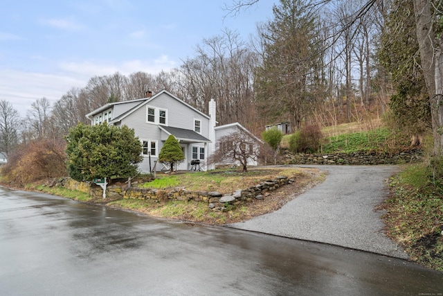 view of home's exterior featuring a chimney and aphalt driveway