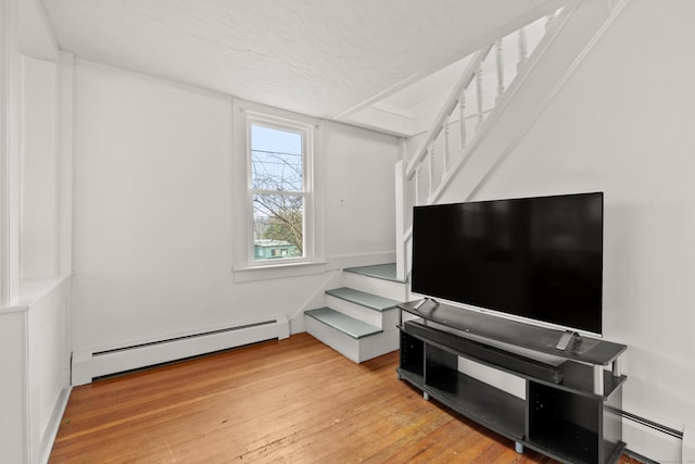 living area with a baseboard radiator, light wood-type flooring, and stairs