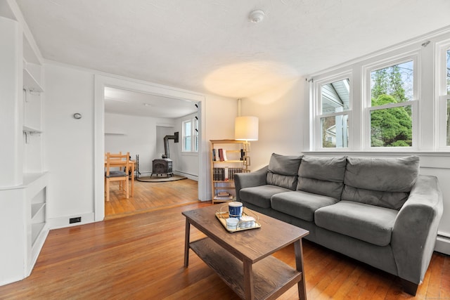 living area with a wood stove, plenty of natural light, and hardwood / wood-style flooring