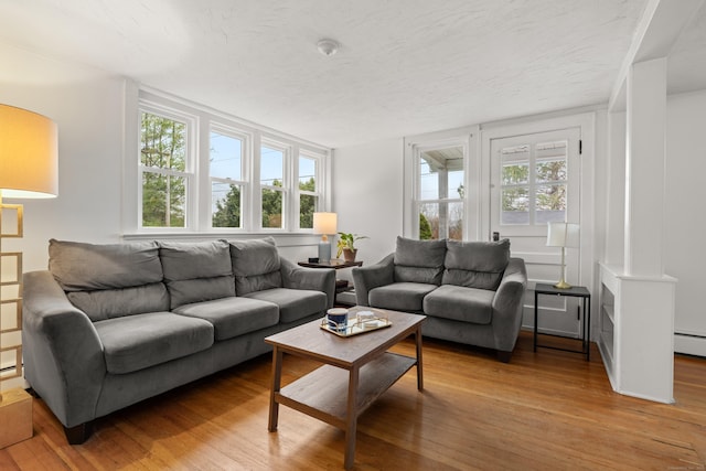 living area featuring a textured ceiling, hardwood / wood-style flooring, and a healthy amount of sunlight