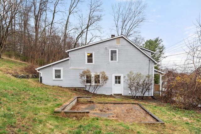 back of property with a vegetable garden and a lawn