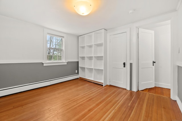 unfurnished bedroom featuring hardwood / wood-style floors and a baseboard radiator