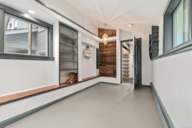hallway with wood walls, finished concrete floors, and a baseboard radiator