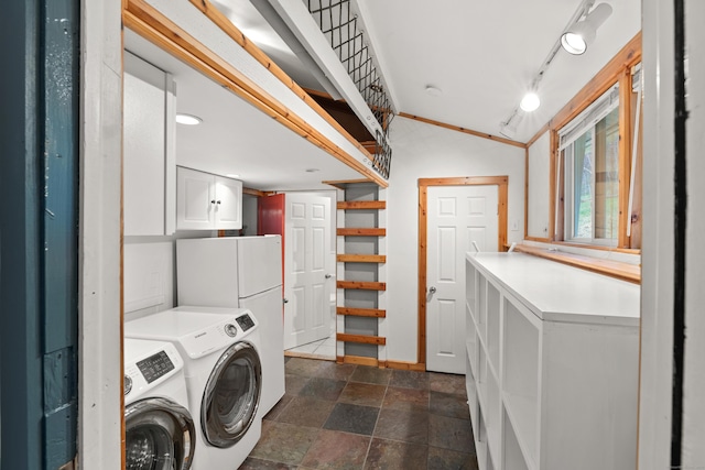 laundry room with stone finish flooring, rail lighting, washing machine and clothes dryer, and cabinet space