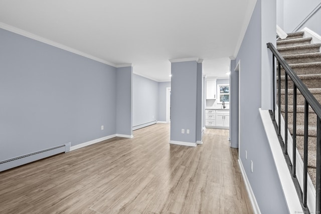 unfurnished living room with light wood-type flooring, ornamental molding, a baseboard heating unit, a sink, and a baseboard radiator