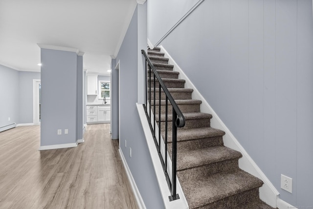 stairs featuring crown molding, baseboards, and wood finished floors