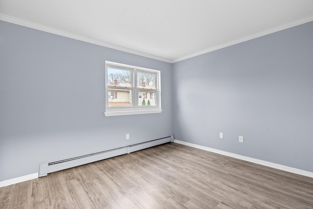 spare room featuring baseboard heating, baseboards, crown molding, and wood finished floors