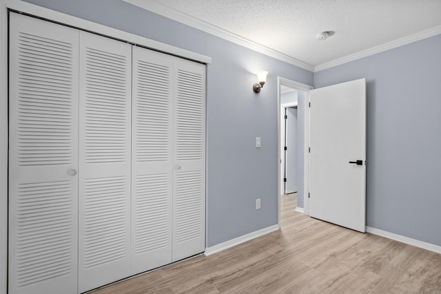 unfurnished bedroom with baseboards, light wood-style flooring, a closet, and crown molding