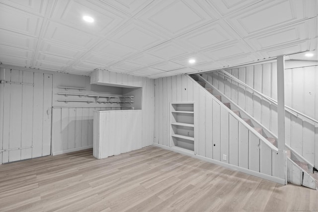 finished basement featuring wooden walls, recessed lighting, stairway, and wood finished floors