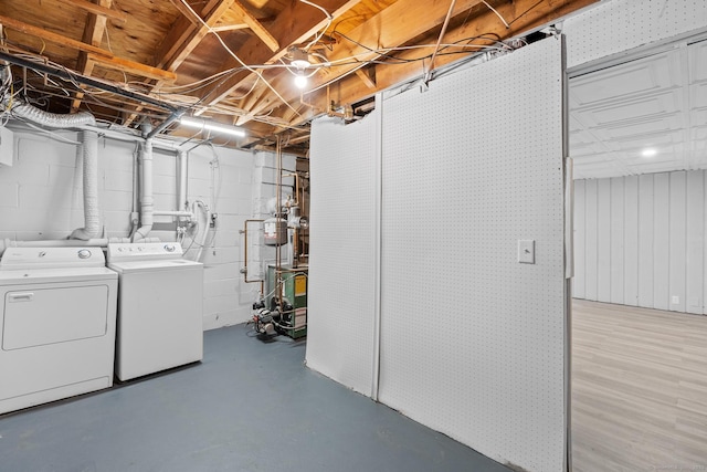 unfinished basement featuring washer and dryer, a heating unit, and concrete block wall
