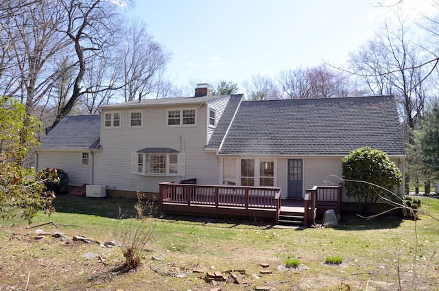 back of house with a chimney, a deck, roof with shingles, and a lawn