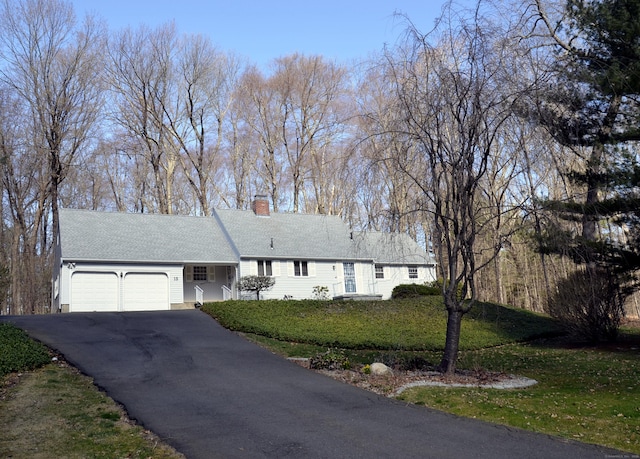 ranch-style home featuring a front lawn, driveway, a chimney, and a garage