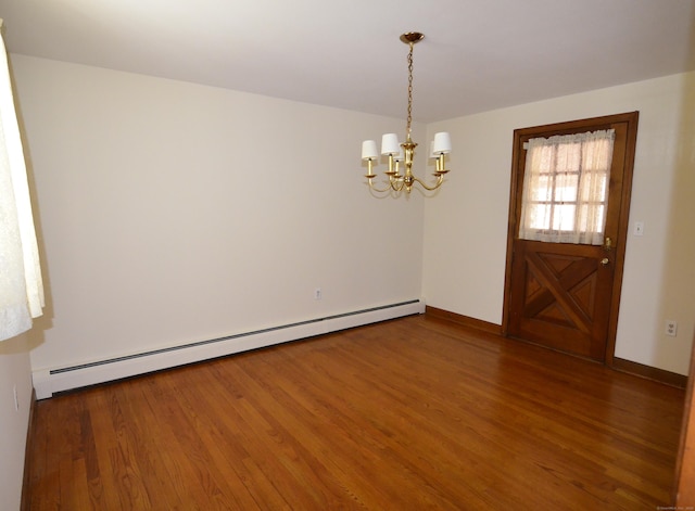 empty room featuring baseboards, a notable chandelier, baseboard heating, and wood finished floors