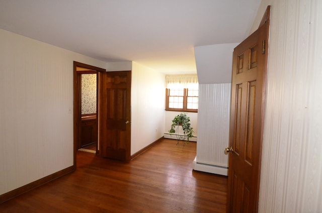 hallway featuring a baseboard heating unit, baseboards, and wood finished floors