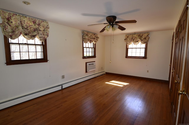 unfurnished bedroom featuring wood finished floors, a ceiling fan, a wall unit AC, baseboards, and a baseboard heating unit