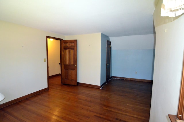 spare room featuring baseboards and dark wood-type flooring
