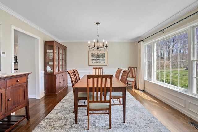 dining space featuring dark wood-type flooring, visible vents, crown molding, and an inviting chandelier