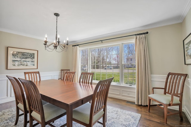 dining room with a wainscoted wall, dark wood-style floors, a decorative wall, crown molding, and a chandelier