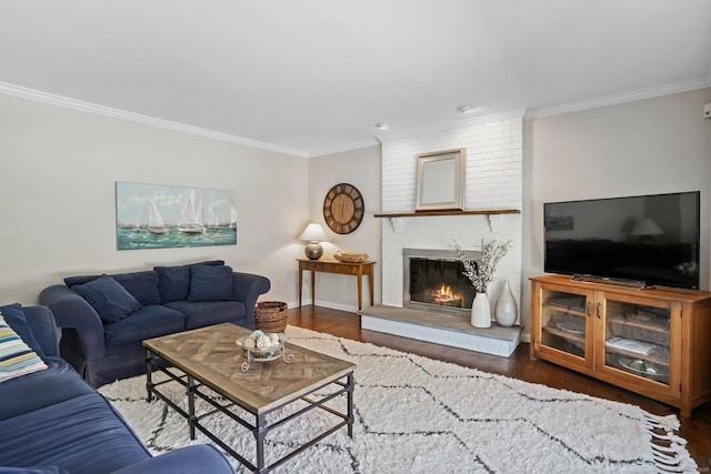 living room featuring wood finished floors, a brick fireplace, baseboards, and ornamental molding