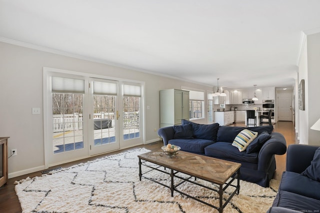 living area with baseboards, ornamental molding, and wood finished floors