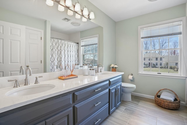 bathroom featuring visible vents, toilet, baseboards, and a sink