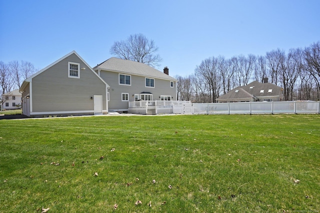 rear view of property featuring fence, a chimney, and a yard
