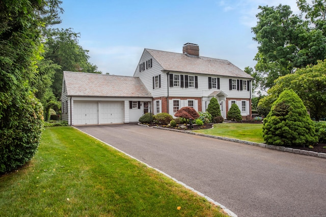 77 Eastfield Rd, Waterbury, CT 06708 - colonial house with a front yard, a chimney, aphalt driveway, brick siding, and an attached garage