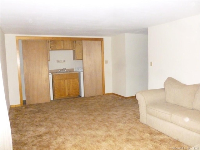 unfurnished living room featuring baseboards, light colored carpet, and a sink
