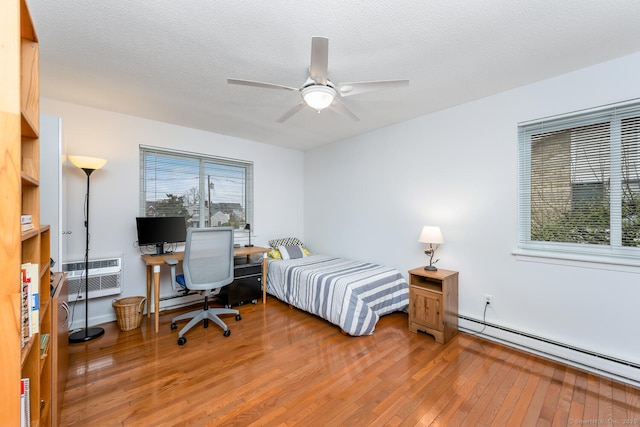 199 Gregory Blvd Apt F1, Norwalk, CT 06855 - bedroom featuring baseboard heating, light wood-type flooring, a wall mounted AC, and a ceiling fan