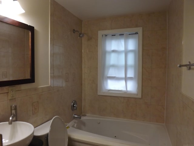 full bathroom with toilet, a sink,  shower combination, and tile walls